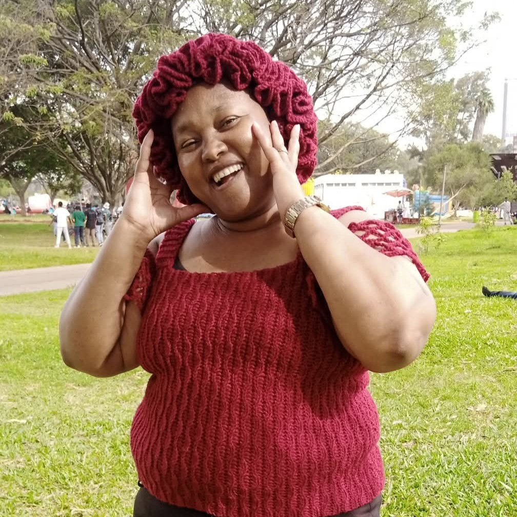 Woman wearing a maroon crocheted top and matching hat, standing outdoors